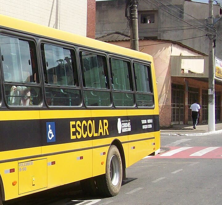 Lateral de um ônibus escolar amarelo, com a faixa preta e a palavra ESCOLAR