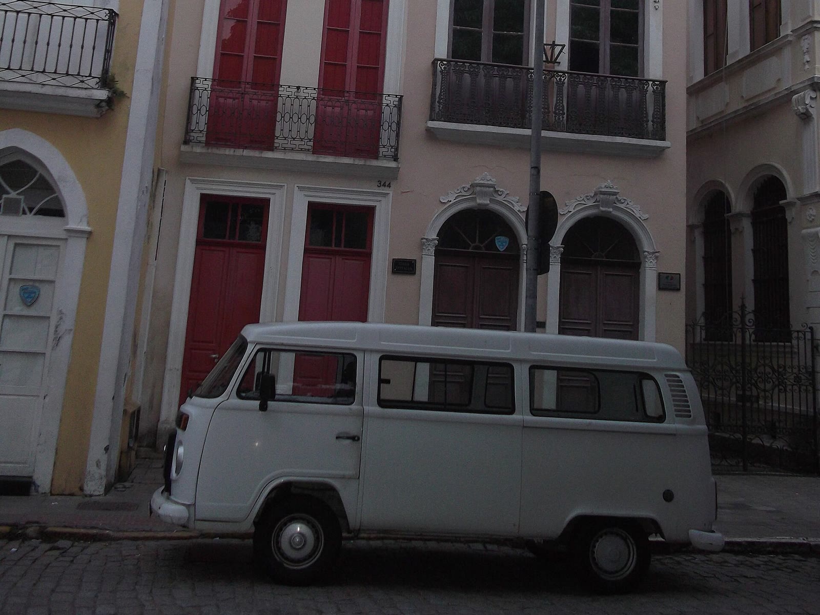 Kombi branca estacionada em frente a um sobrado antigo