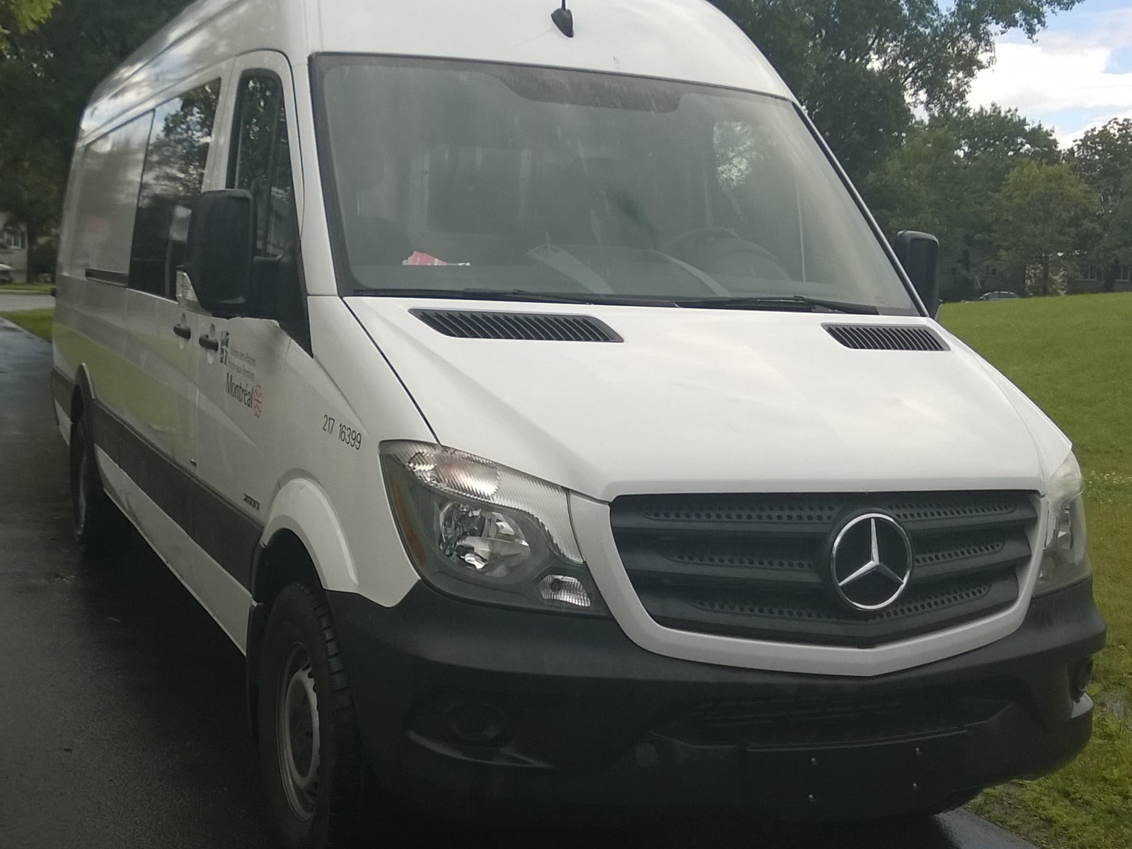 Van branca de passageiros estacionada na rua, vista de frente
